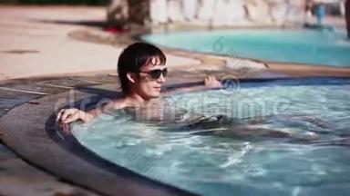 戴太阳镜的英俊的年轻人躺在游泳池里休息。 幸福，暑期旅游度假酒店。 1920x1080